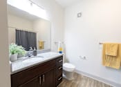 Thumbnail 49 of 66 - A bathroom with a white toilet, sink, and wooden floors.