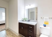 Thumbnail 59 of 66 - A bathroom with a white toilet and a counter with a mirror above it.