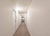 Thumbnail 16 of 81 - A long hallway with doors on the left and a light on the right.