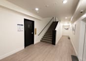 Thumbnail 17 of 81 - A hallway with a staircase and a door on the left side.