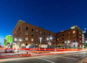 Thumbnail 8 of 81 - A street view of a city at night with a building in the background and a red fence in the foreground.