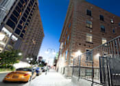 Thumbnail 12 of 81 - A city street at night with a yellow cab and a brick building.