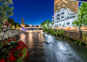Thumbnail 25 of 81 - A nighttime view of a river with a building in the background.