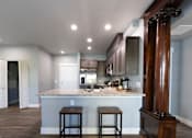Thumbnail 37 of 81 - A kitchen with a marble countertop and bar stools.