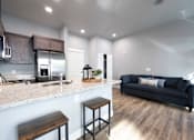 Thumbnail 41 of 81 - A modern kitchen with a bar stool and a black couch.