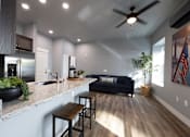 Thumbnail 42 of 81 - A modern kitchen with a bar stool and a black couch.