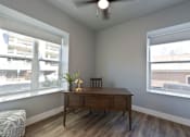 Thumbnail 43 of 81 - A room with a wooden desk and a chair with a lamp on it.