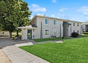 Thumbnail 5 of 24 - A residential building with a green lawn in front.