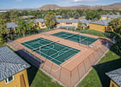 Thumbnail 13 of 24 - A tennis court surrounded by a fence and buildings.