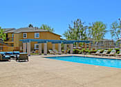 Thumbnail 22 of 24 - A large swimming pool in front of a yellow building with lounge chairs around it.