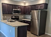 Thumbnail 9 of 19 - View of kitchen  with granite counters, stainless appliances, and brown cabinets
