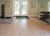 Thumbnail 31 of 33 - a fitness room with weights and a rug on a wood floor