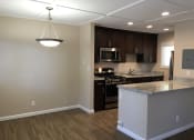 Thumbnail 5 of 34 - view of kitchen and dining area with wood look flooring, stone counters, stainless appliances, brown cabinets, recessed lighting, and a chandelier in the dining area