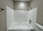 Thumbnail 4 of 28 - A white bathroom with a white tub and a white shower head.