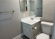 Thumbnail 6 of 28 - A white bathroom with a sink, toilet and mirror.