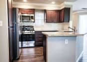 Thumbnail 3 of 54 - Kitchen view with brown cabinets, stone counters, tile backsplash, and stainless appliances