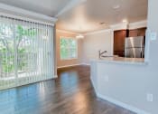 Thumbnail 2 of 54 - View into kitchen and dining area with access to private balcony, wood look flooring, brown cabinets, stainless appliances, and stone counters