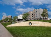 Thumbnail 1 of 65 - a building with a park and a sign in front of it  at Parks Residential - Richardson, Richardson, 75082