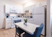 Thumbnail 12 of 65 - a kitchen with white appliances and a white table with blue chairs at Parks Residential - Richardson, Richardson, 75082