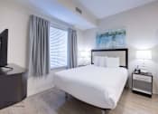 Thumbnail 19 of 65 - a bedroom with a white bed and a tv at Parks Residential - Richardson, Richardson, Texas