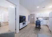 Thumbnail 16 of 65 - a living room and kitchen with white cabinets and a table with a chair at Parks Residential - Richardson, Richardson