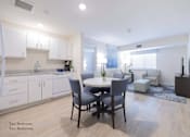 Thumbnail 24 of 65 - a kitchen and living room with white cabinets and a table and chairs at Parks Residential - Richardson, Texas