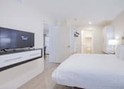 Thumbnail 35 of 65 - a bedroom with a large bed and a tv at Parks Residential - Richardson, Richardson, Texas