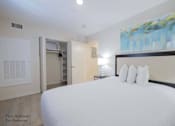 Thumbnail 54 of 65 - a bedroom with a large bed and a door to a bathroom at Parks Residential - Richardson, Richardson, Texas