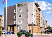 Thumbnail 1 of 12 - a building with a flag and cars parked in front of it at Parks Residential - Denver, Centennial, CO 80111