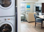 Thumbnail 9 of 12 - a living room with a washing machine and a kitchen with a table and chairs at Parks Residential - Denver, Centennial Colorado