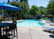 Thumbnail 15 of 20 - A pool area with chairs and umbrellas.