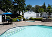 Thumbnail 16 of 20 - A swimming pool with a blue umbrella and a white house in the background.