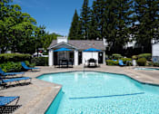 Thumbnail 13 of 20 - A pool with a blue umbrella and chairs.