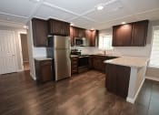 Thumbnail 9 of 27 - View of open kitchen with stone counters, tile backsplash, stainless appliances, brown cabinets, recessed lighting, and wood look flooring