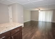 Thumbnail 10 of 27 - view of living room from kitchen with wood look flooring, ceiling fan, and private patio/balcony access through sliding glass door