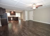 Thumbnail 7 of 27 - View from living room to kitchen with wood look flooring, stainless appliances, brown cabinets, and ceiling fan