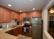 Thumbnail 10 of 26 - View of kitchen with stone counters, stainless appliances, brown cabinets