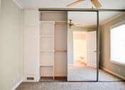 Thumbnail 17 of 25 - View of large sliding glass mirror door closet with built in shelving and carpet in bedroom