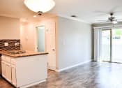 Thumbnail 25 of 25 - Living room view with wood look flooring, sliding glass door leading to private patio, partial view of kitchen counter