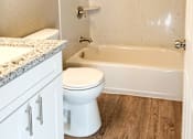 Thumbnail 6 of 12 - bathroom with wood look flooring, stone vanity, toilet, and tub shower combo