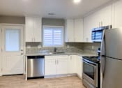 Thumbnail 1 of 12 - kitchen with stone counters, stainless appliances, white cabinets, recessed lighting and wood look flooring