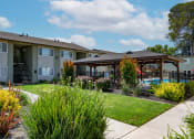 Thumbnail 21 of 34 - View of exterior building, well landscaped courtyard, gated pool area with covered area with picnic table and seating