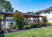 Thumbnail 22 of 34 - View of well landscaped courtyard with gated community pool in background. Has covered area with seating and picnic
