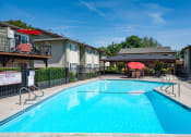Thumbnail 30 of 34 - View of gated community pool with seating under umbrellas and covered area with seating and picnic table