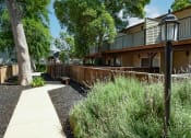 Thumbnail 20 of 34 - View of sidewalk winding between private patio/balcony with blooming landscaping and trees shading the sidewalk