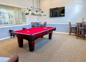 Thumbnail 16 of 19 - a red pool table in a game room with chairs and a tv