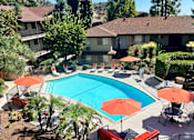 Thumbnail 27 of 28 - a swimming pool with umbrellas in front of a house