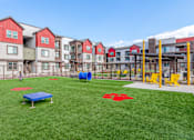 Thumbnail 50 of 76 - A playground area with a blue mat and red star on the grass in front of apartment buildings.