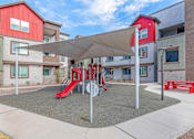 Thumbnail 56 of 76 - A playground with a red slide and a grey canopy.