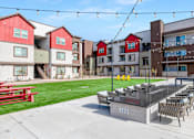 Thumbnail 63 of 76 - A red and white building with a patio and chairs.